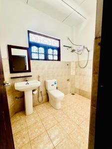 a bathroom with a toilet and a sink and a window at Asiri guest house in Dickwella +14 photos