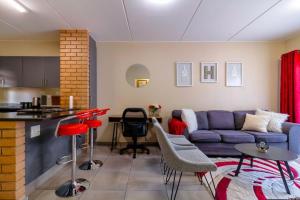 a living room with a blue couch and a kitchen at The Waterfallcity Charm next to Mall of Africa in Midrand