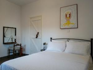 a bedroom with a white bed with a picture on the wall at Armaki in Páliros