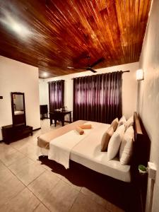 a bedroom with a large bed with a wooden ceiling at Asiri guest house in Dickwella