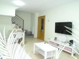 ein weißes Wohnzimmer mit Fernseher und Tisch in der Unterkunft Brezo 2 in Yunquera de Henares