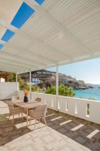 a white patio with a table and chairs and the ocean at Nikos Studios in Lefkos Karpathou