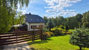 a house with a fence in front of a yard at Polna Zagroda - domek do wynajęcia in Kielce