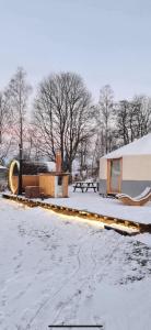 a snow covered yard with a house and a building at Yurt in Be Bernartice in Bernartice