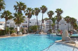a large swimming pool with palm trees and buildings at Apartamento isabel golf center in Almería