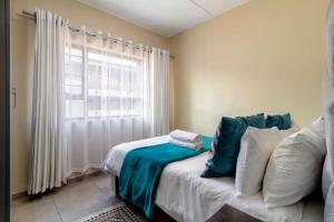 a bedroom with a bed with pillows and a window at The Waterfallcity Charm next to Mall of Africa in Midrand +34 photos