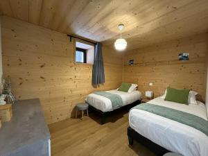 two beds in a room with wooden walls at Appartement Chalet Louison in Les Gets