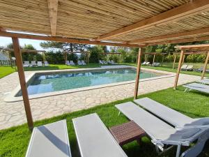 a swimming pool with two lounge chairs and a pergola at Agriturismo e Maneggio Poggio Leone in Gambassi Terme