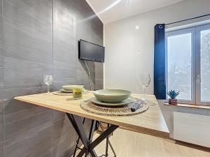 a dining table with two wine glasses and a television at Cosy & Charmant - centre et tranquillité in Erstein