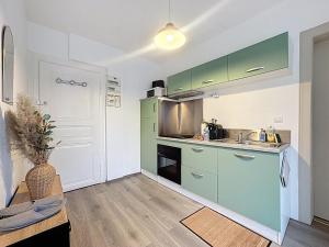 a small kitchen with green cabinets and a table at Cosy & Charmant - centre et tranquillité in Erstein