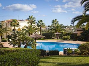 a swimming pool with palm trees and a building at Apartment En Capillo in Manacor