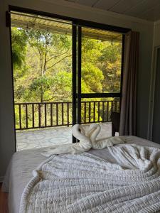 a bedroom with a bed and a large window at Cabaña BosKaL in Quesada