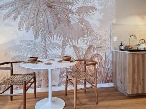 a table and chairs in a kitchen with a palm wallpaper at La Suite BALI, Charme et Confort, Hyper centre in La Roche-sur-Yon