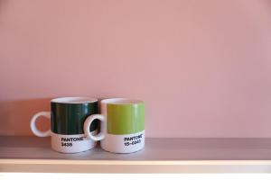 two green and white coffee mugs sitting on a shelf at Design Apartment Plön in Plön
