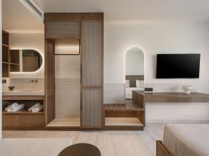 a bathroom with a walk in shower with a television at Sunny Bay Hotel in Kissamos