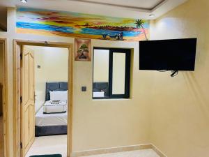 a room with a flat screen tv and a bedroom at Waves Surf House in Taghazout