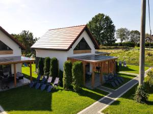 a house with a pitched roof with chairs in the yard at Domki Górkło in Górkło +21 photos