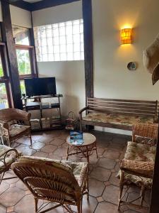 a living room with a couch and chairs and a tv at Canto do Cururuá - IlhaBela in Ilhabela