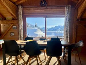 a dining room with a table and chairs and a large window at Chalet Lucien, Jacuzzi, Les 3 Vallées in Villarly