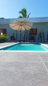 a swimming pool with an umbrella and tables and chairs at Bangalô em uma área próxima a praia e centro in Porto Seguro