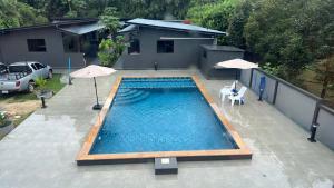 a swimming pool with two umbrellas and a house at Dan Mai Homestay in Trat