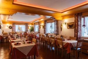 a dining room with tables and chairs and windows at Hotel Edelweiss in Val di Zoldo