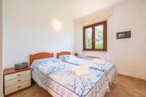 a bedroom with two beds and a window at Villa Del Sole- in Costa Rei