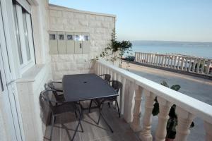 a table and chairs on a balcony with a view of the ocean at Apartmani Ivo 2 in Podstrana