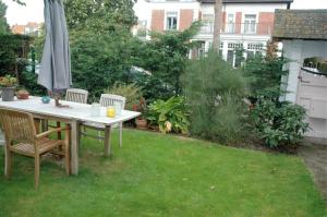 a table with chairs and an umbrella in a garden at B&B Le Maquis in De Haan