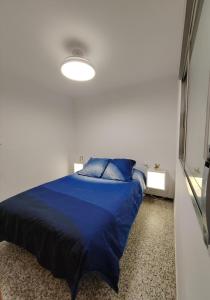 a bed in a room with a blue comforter at Vistal Mar in Puerto de Sagunto