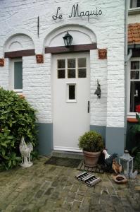 a white front door of a white brick house at B&B Le Maquis in De Haan