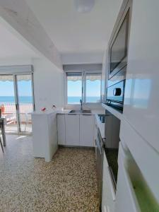 a kitchen with white cabinets and a view of the ocean at Vistal Mar in Puerto de Sagunto
