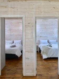 two beds in a room with wooden walls at Eindelik on de Lange in Graskop +9 photos