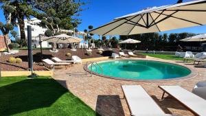 a swimming pool with chairs and an umbrella at Al Grande Pino - Private pool, Jacuzzi and amazing Sunset in Campofelice di Roccella