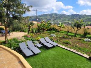 a group of lounge chairs sitting on a lawn at House with a heated pool for your exclusive use in Santa Brígida