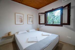 a bedroom with a large white bed with a window at Villa Olivia in Loutraki +30 photos