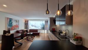 a kitchen and living room with black counter tops at Panorama Apartments - Steinbock Lodges in Zell am See