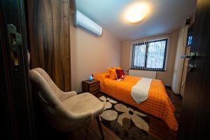 a bedroom with a bed and a chair and a window at Къща за гости Милена in Apriltsi