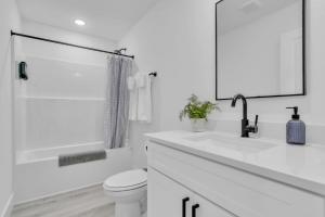 a white bathroom with a toilet and a sink at 3 BR Downtown Spartanburg- Upscale& Work Ready "Sweet Carolina Cottage" in Spartanburg +11 photos