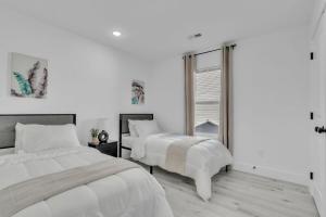 a white bedroom with two beds and a window at 3 BR Downtown Spartanburg- Upscale& Work Ready "Sweet Carolina Cottage" in Spartanburg