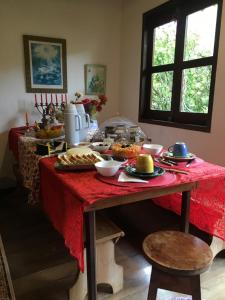 a table with a red table cloth with food on it at Recanto da Deusa in Bocaina de Minas