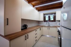 a kitchen with white cabinets and a wooden counter top at Villa Olivia in Loutraki