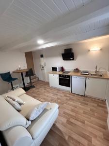 a living room with a white couch and a kitchen at Le petit cocon in Pont-de-Veyle