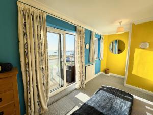 a room with yellow and blue walls and a window at Poole Harbour View in Poole