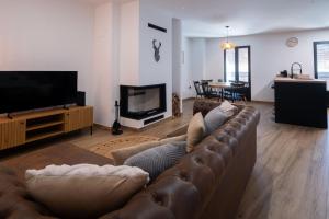 a living room with a brown couch and a television at Casa Los Yayos in Segorbe