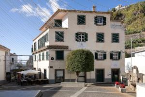 a white building with a tree in front of it at Solful at the Nomads Village Ponta do Sol in Ponta do Sol