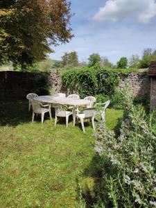 a table and chairs in a yard with a stone wall at Le Clos du Château in Rully