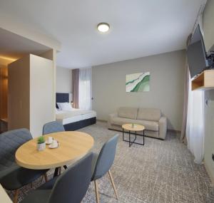 a hotel room with a couch and a table and chairs at Hotel NOVA Inn Sarajevo in Sarajevo