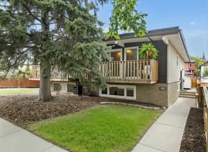a house with a deck and a tree at Entire Home - 2 Separate Units in Calgary