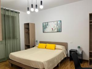 a bedroom with a bed with yellow pillows on it at Olympic Lodge in Milan